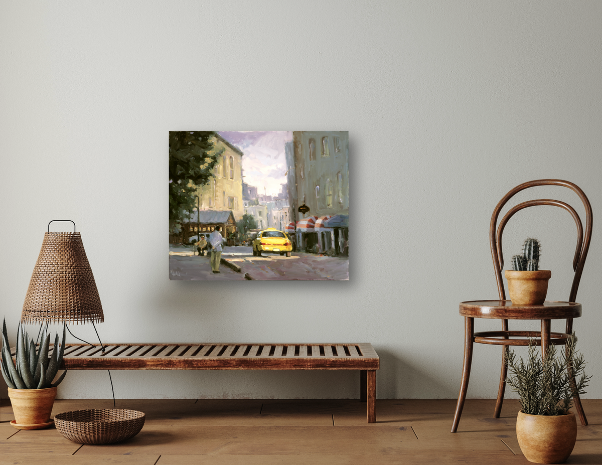 Canvas print of a city street scene featuring a yellow taxi, soft pastel buildings, and trees, displayed on a gray wall above a wooden bench and next to a wooden chair with potted plants.