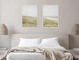 Two framed canvas prints above a neutral beige bed, featuring soft green coastal dunes on the left and a sandy beach meeting calm ocean waves on the right.