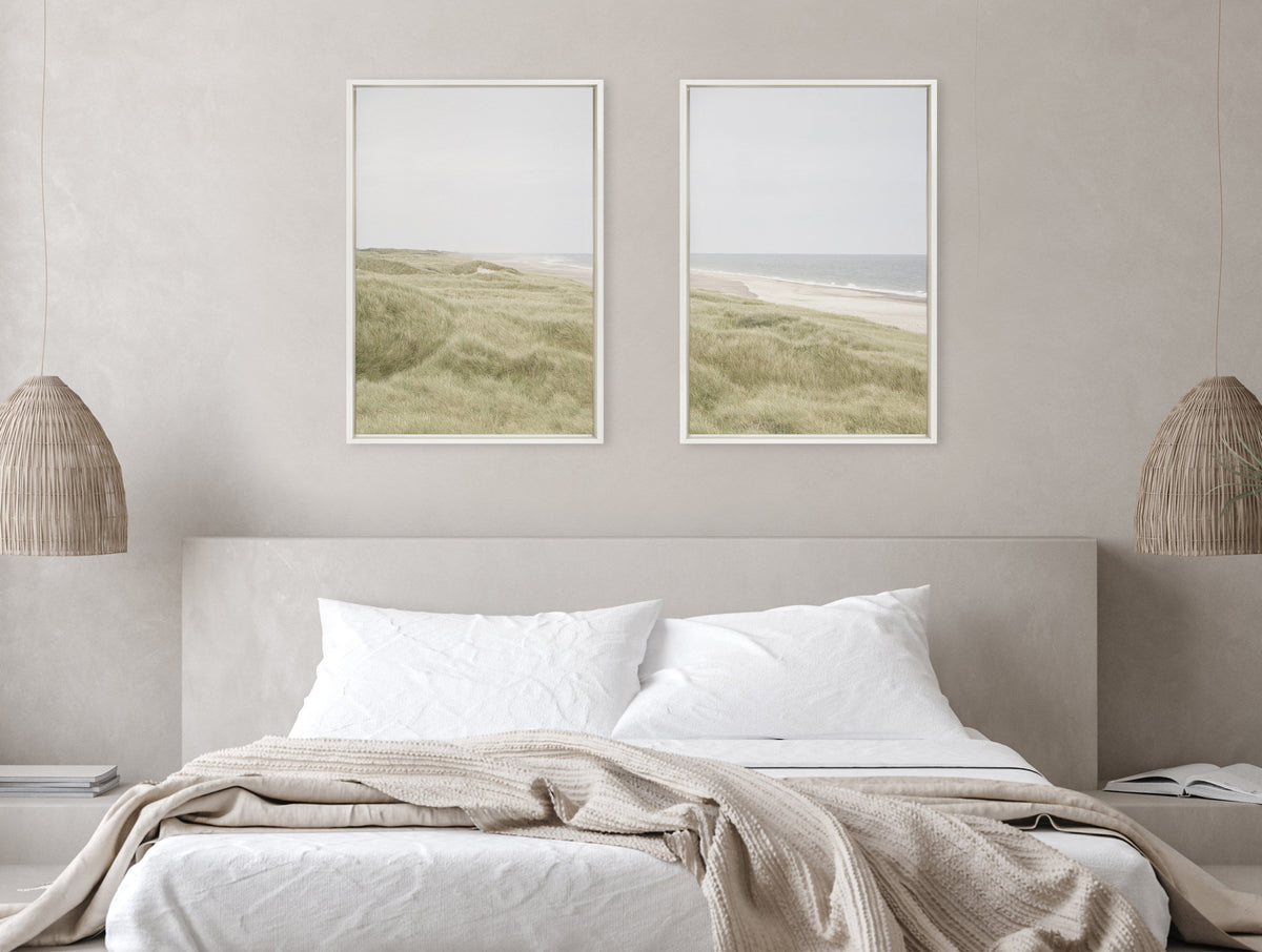 Two framed canvas prints above a neutral beige bed, featuring soft green coastal dunes on the left and a sandy beach meeting calm ocean waves on the right.