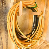 Hose & Extension Cord Organizer Hook mounted on a shed wall holding garden hoses