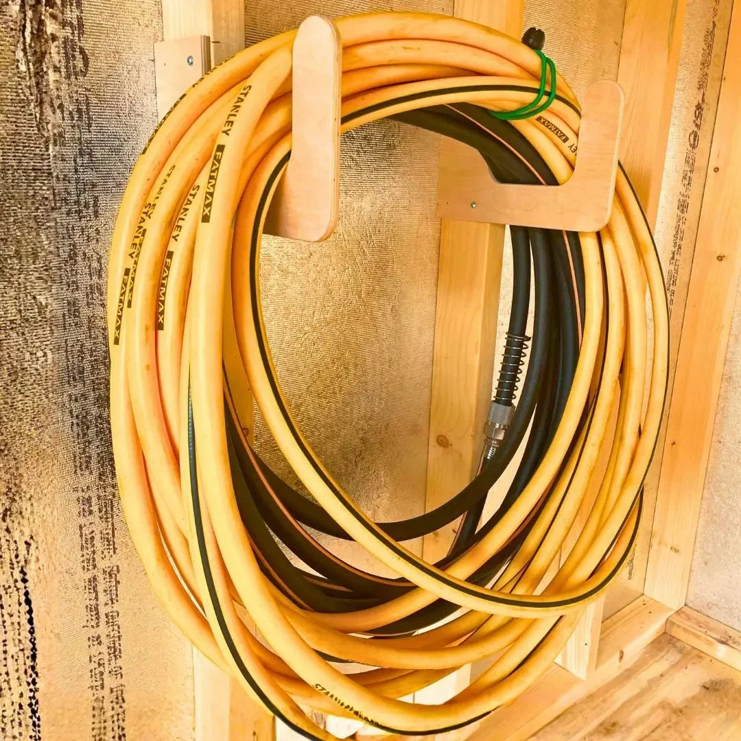 Hose & Extension Cord Organizer Hook mounted on a shed wall holding garden hoses