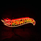 Red and yellow neon sign shaped like a flame with the words 'Hot Wheels' glowing prominently against a black background.