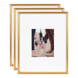 Set of three gold photo frames with beaded detailing, each holding an image of a black and white French bulldog standing on a floor with two people's legs visible.