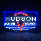 Neon sign with blue rectangular border, white uppercase text 'HUDSON' across the top, 'SALES' on left and 'SERVICE' on right, centered red-orange chevron shape.