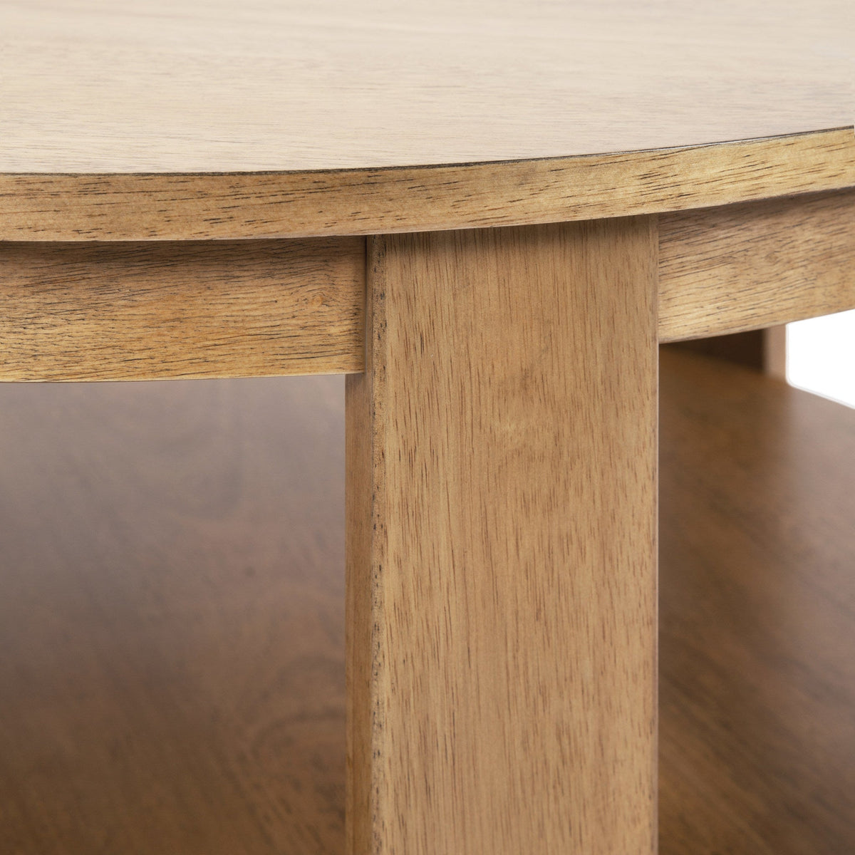 Close-up of a round wood coffee table leg and underside of the top showing light natural wood grain and smooth edges with a shelf beneath.