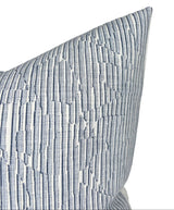 Close-up of a denim blue pillow cover with a textured geometric stripe pattern featuring varying thicknesses and subtle raised lines.