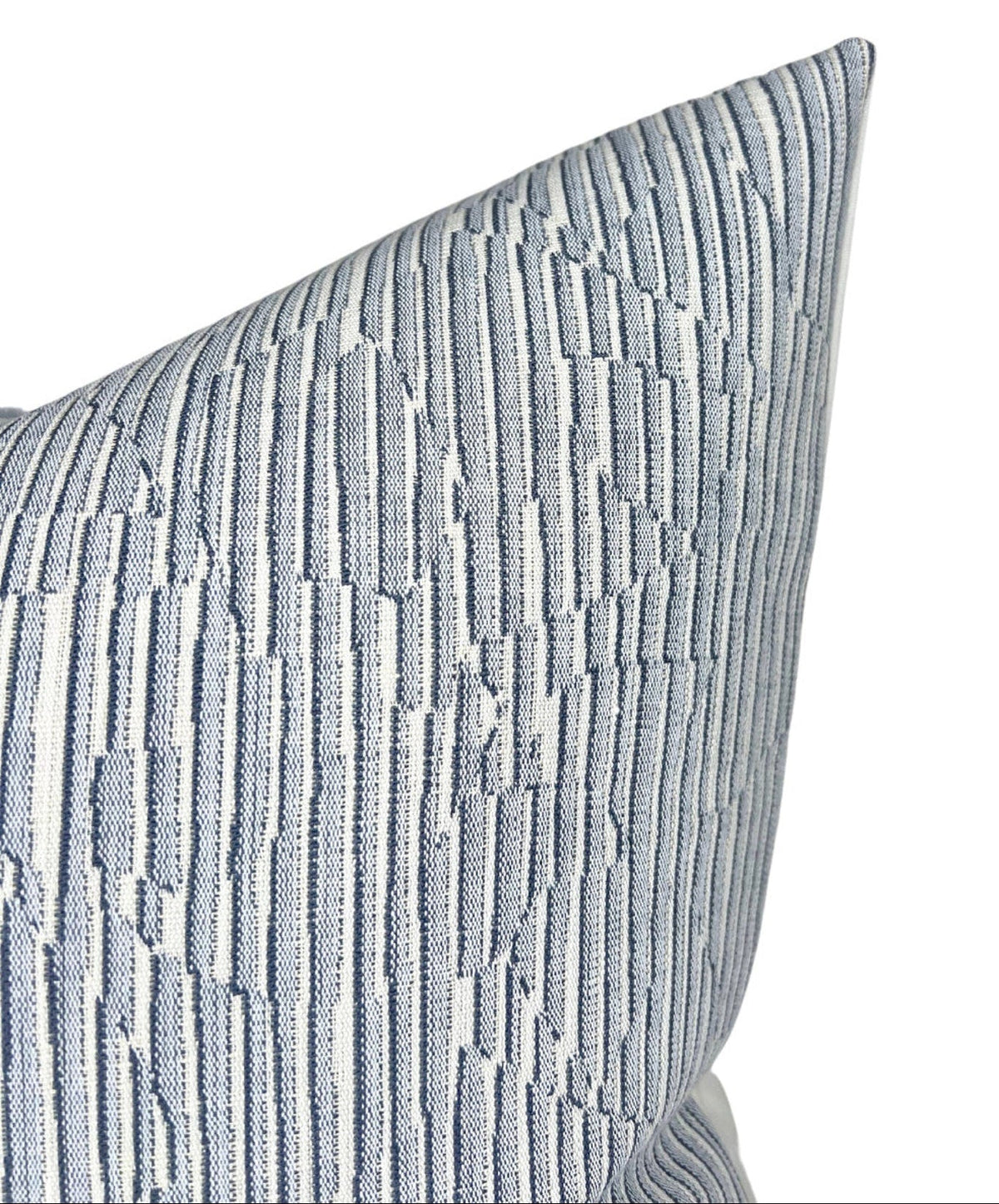 Close-up of a denim blue pillow cover with a textured geometric stripe pattern featuring varying thicknesses and subtle raised lines.