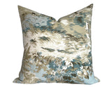 Square pillow with a scenic toile pattern in light blue, beige, and white depicting foliage and clouds on a textured fabric background.