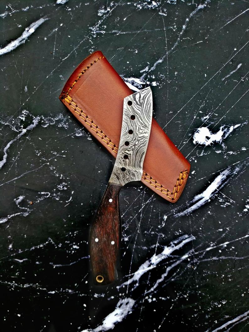 Mavado Damascus Cleaver Blade Knife with rosewood handle and leather sheath resting on a cloth