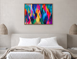Colorful abstract canvas with bright blue, pink, orange, and gold brushstrokes accented by black and white patterns in a wooden frame above a neutral-toned bed.