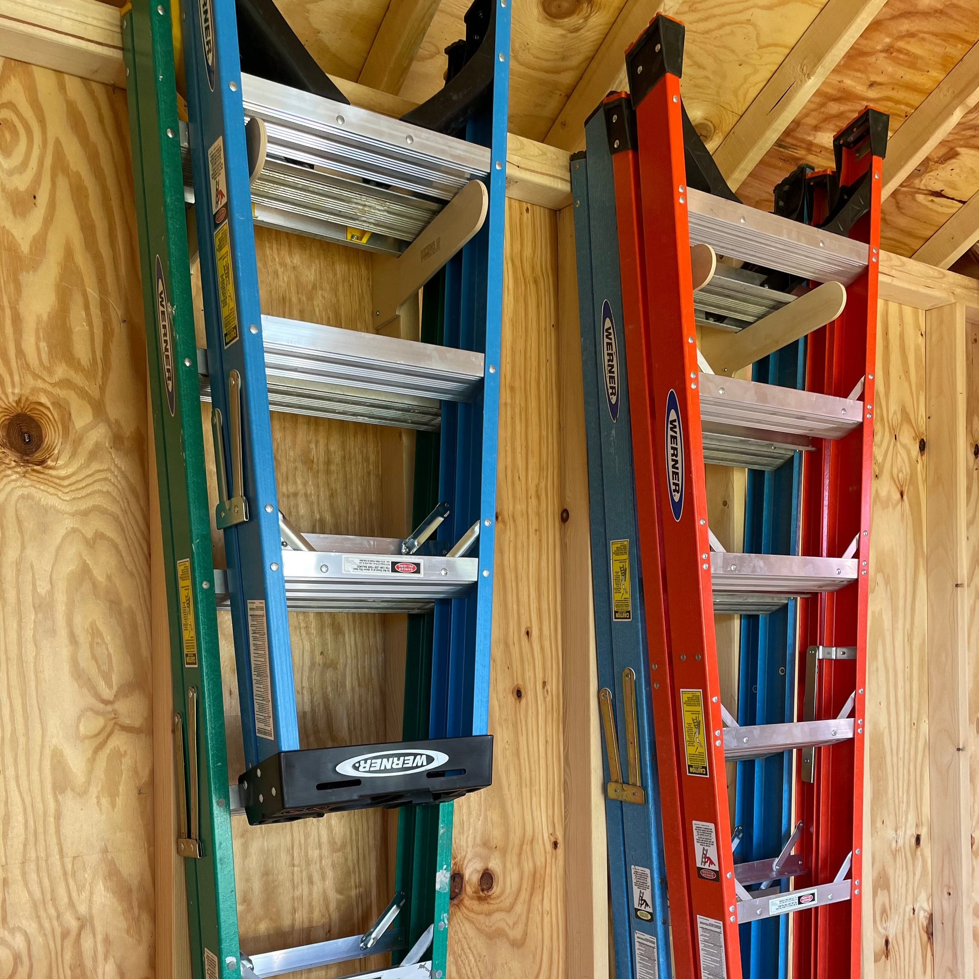 Step Ladder Organizer Rack mounted on a shed wall holding two step ladders