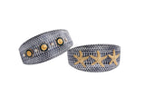 Two textured, navy and white snake-patterned cuffs adorned with gold embellishments: one with three gold stars, the other with gold coins and smaller studs.