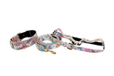 White Italian leather collar, leash, and harness set featuring a colorful floral mosaic pattern and gold classic hardware on a white background.