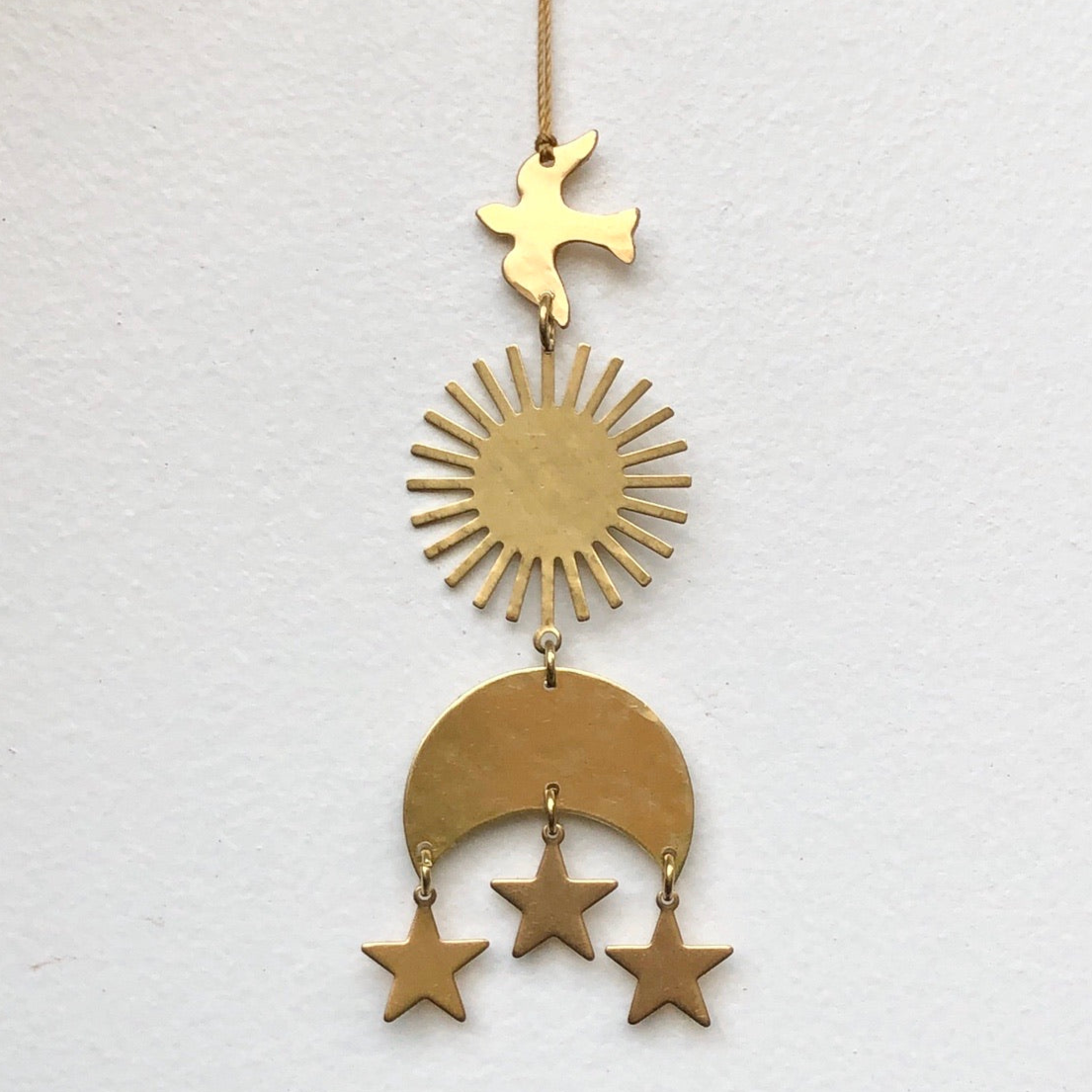 Brass wall hanging ornament with organic hand-cut and hammered texture on beige background