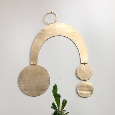 Sun Halo brass wall hanging by Vida + Luz, hand-cut and brushed, shown on neutral wall