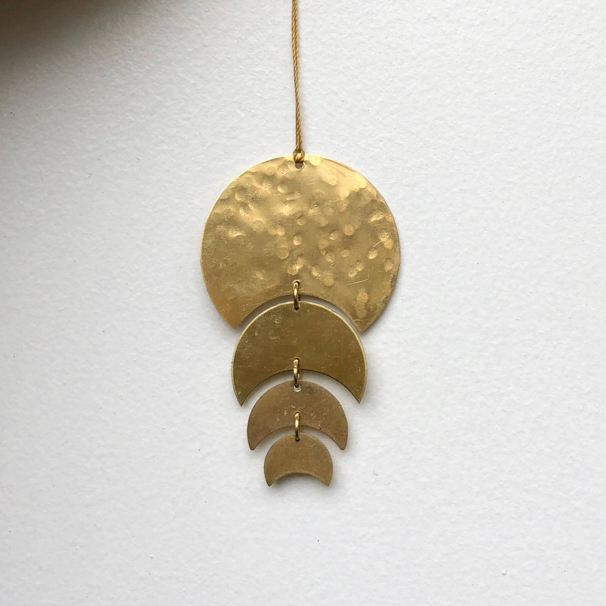 Just a Phase Ornament hanging, showing its thin brass phases with a hanging cord