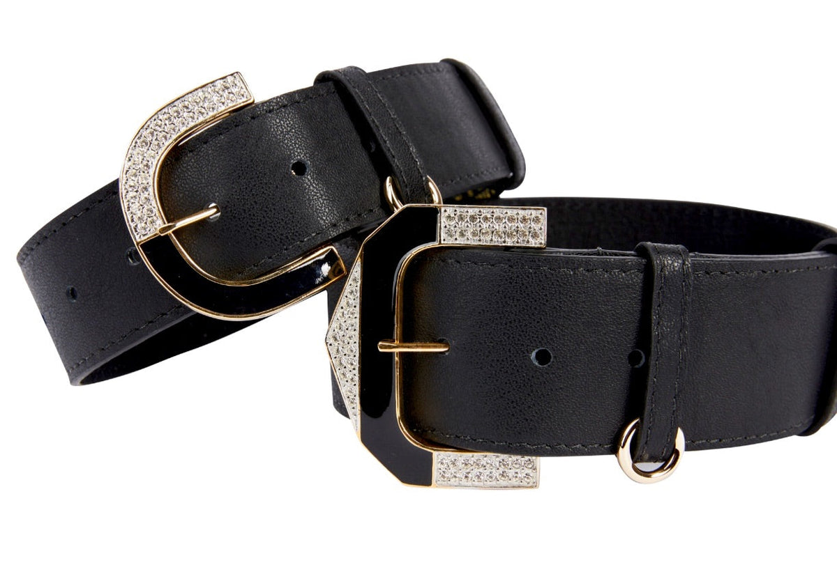 Two black leather collars with wide straps, featuring gold-tone buckles adorned with sparkling rhinestones, shown against a white background.