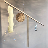 Goldy Suncatcher wall hanging showing hand-cut hammered brass, vintage glass crystal, and raw wood elements