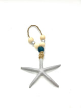 Silver-colored textured starfish ornament with a jute loop and decorative beige and blue beads for hanging