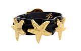 Black Italian leather collar adorned with three textured gold starfish-shaped embellishments, shown from a side angle on a white background.