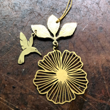 Hibiscus Hummingbird Ornament made of hammered brass hanging against a neutral backdrop