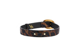 Slim bracelet with brown and black abstract leopard print leather and a large round vintage gold-toned clasp, displayed on a white background.