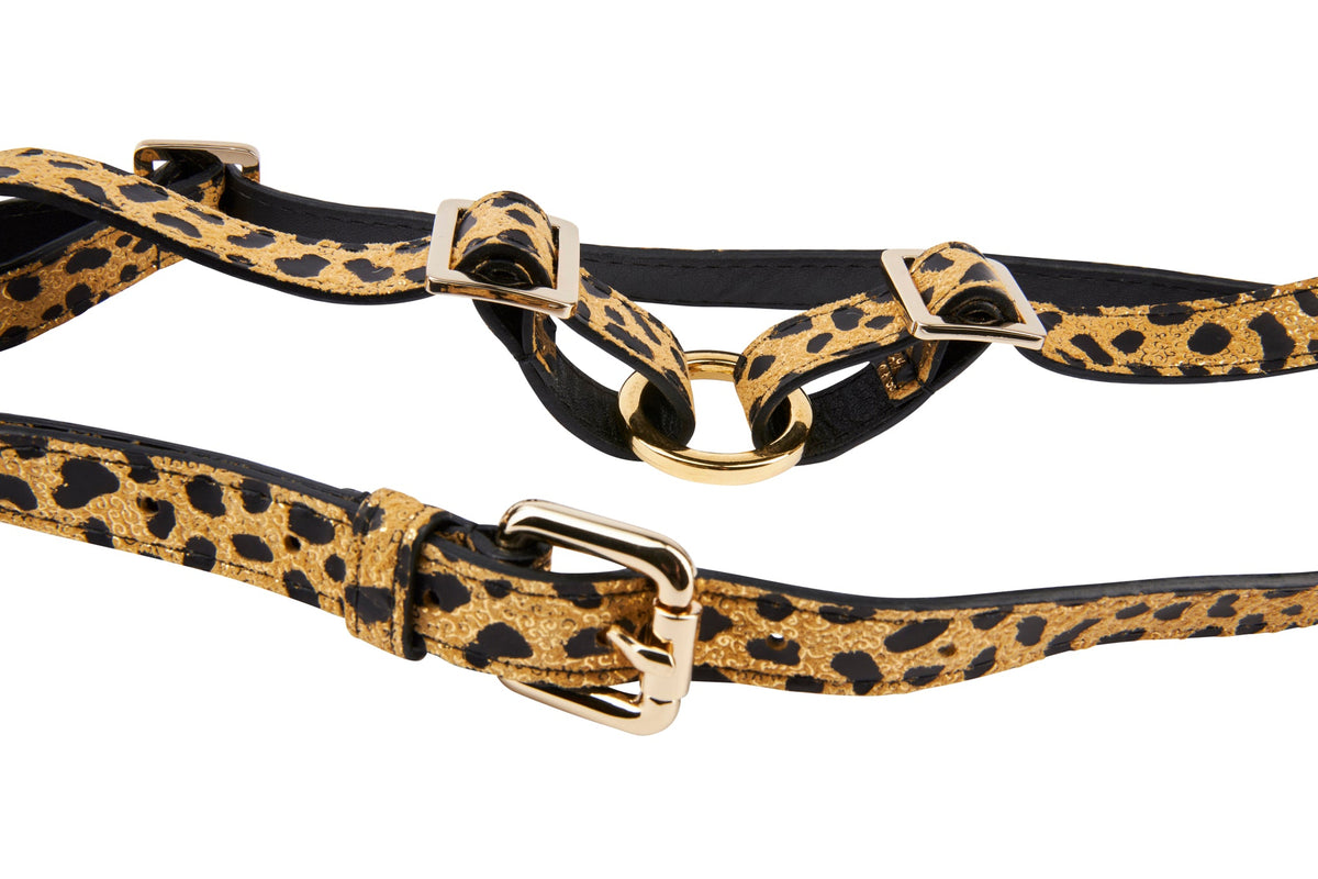 Leather harness with leopard print pattern featuring gold-tone metal rings and adjustable buckles, displayed on a white background.