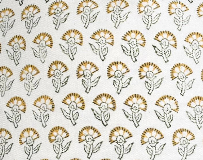 Close-up of a white fabric with a repeated pattern of stylized marigold flowers in mustard yellow and black outlines, arranged in evenly spaced rows.