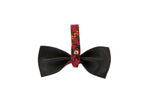 Black leather bowtie with a red and yellow plaid strap featuring a gold button in the center, displayed against a plain white background.