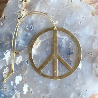 Choose Peace brass ornament by Vida + Luz hanging indoors