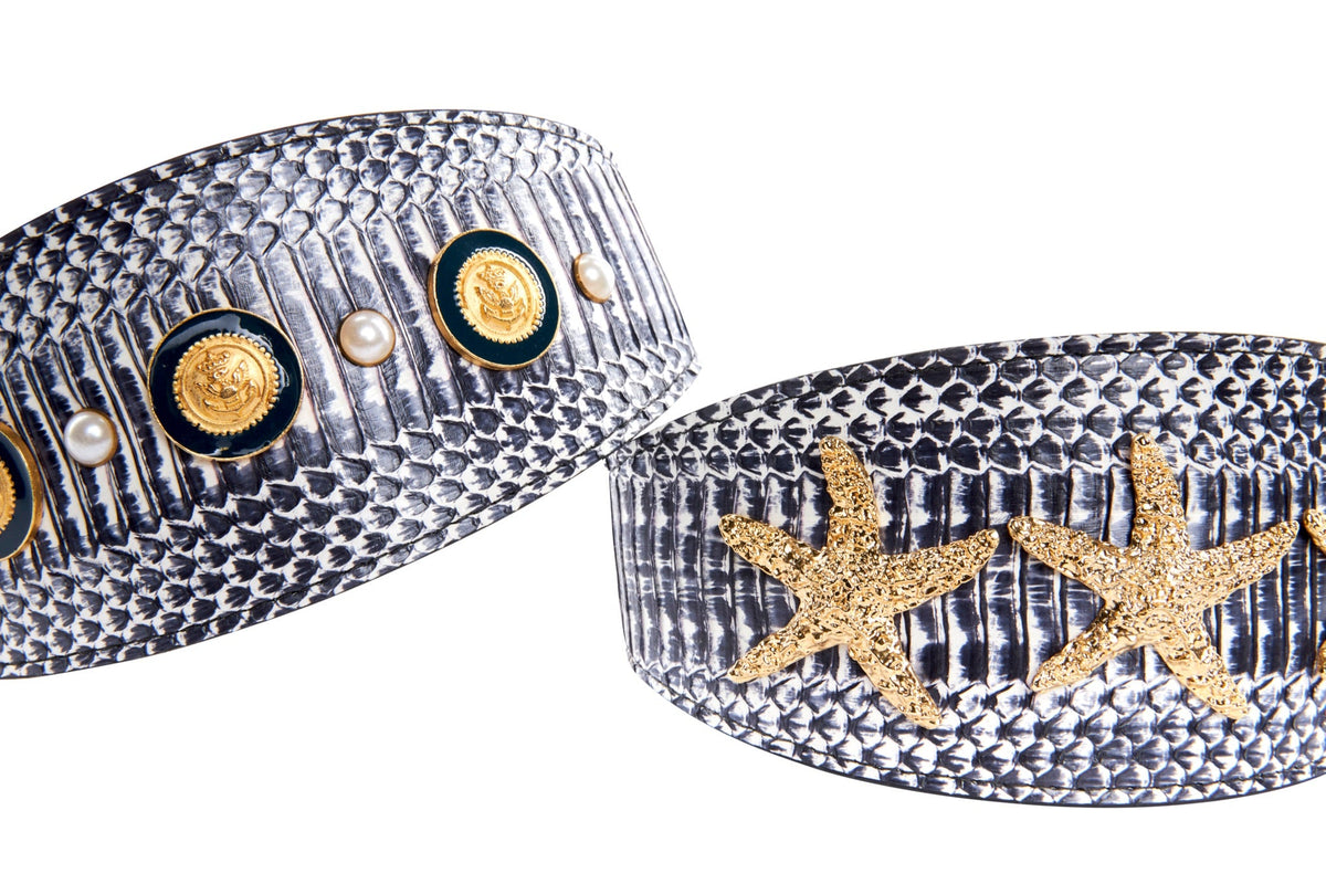 Two white and navy snake-patterned resin bangles with nautical-themed gold accents; one features gold medallions and pearls, the other gold starfish embellishments.