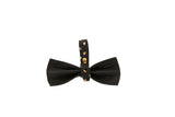 Black leather bowtie featuring a strap with evenly spaced round gold studs, shown on a white background
