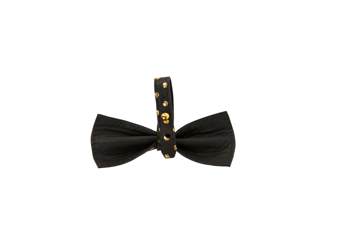 Black leather bowtie featuring a strap with evenly spaced round gold studs, shown on a white background