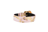 Soft pink snake-patterned collar with gold-tone buckle and Swarovski crystal hardware, shown coiled on a white background.