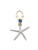 White textured starfish ornament with jute string and natural wood beads, including a single large blue bead above the starfish.