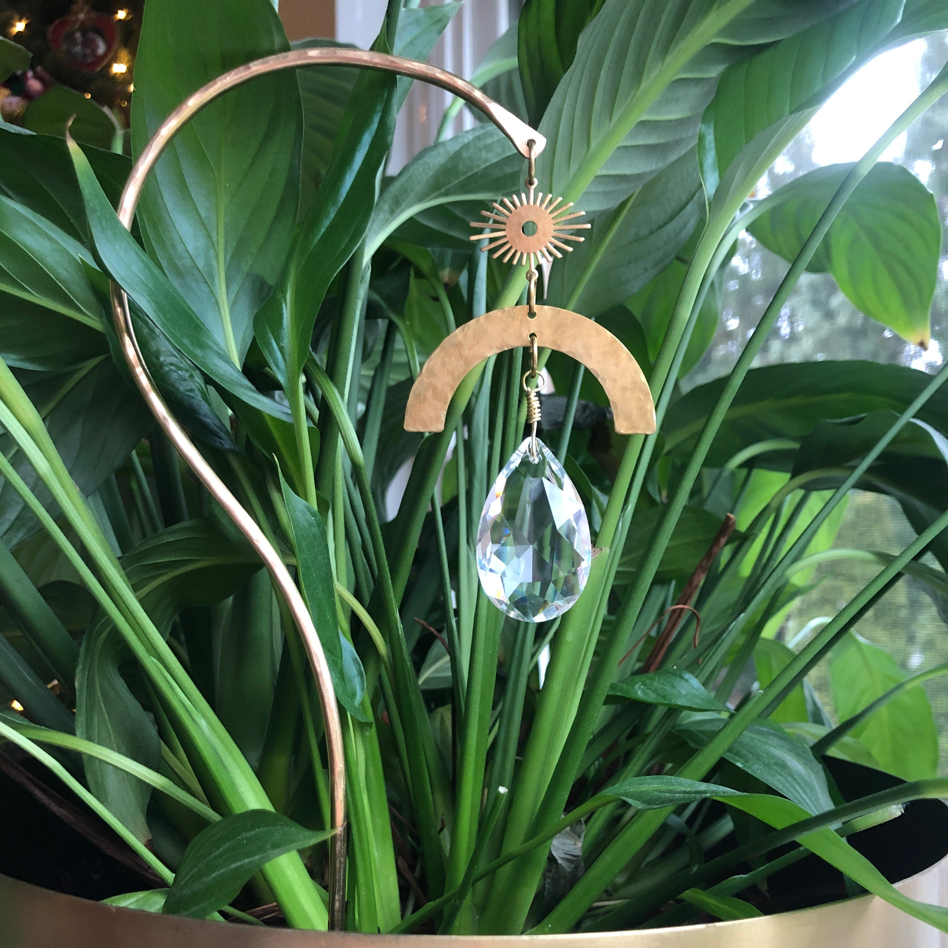 Planty Suncatcher Stick- Solara showing brass wire, driftwood, and crystal hanging in sunlight