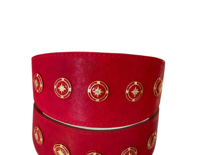 Red distressed Italian leather pet collar with vintage star rivets on a wooden surface