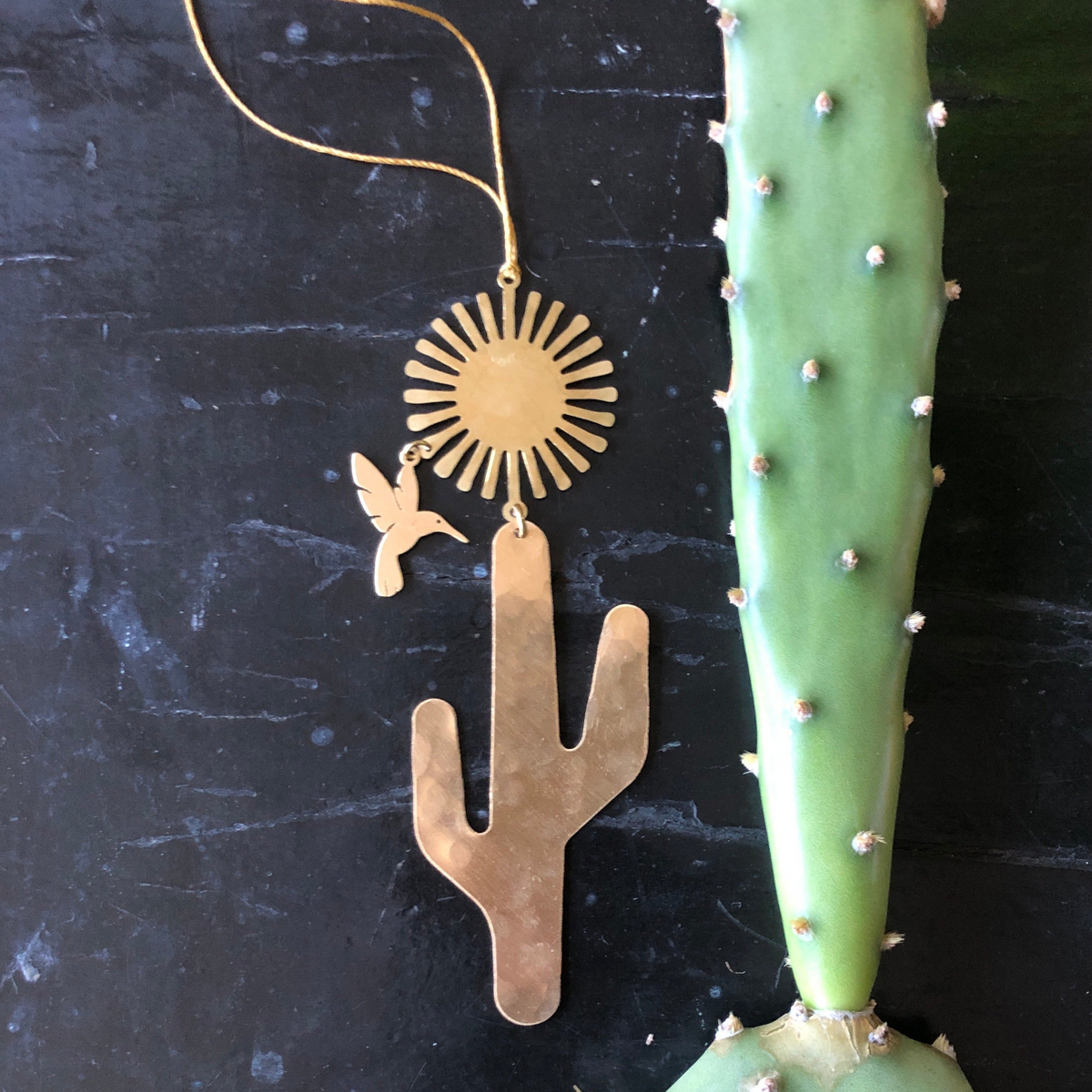 Desert Dream Ornament hanging indoors, showing textured hammered brass surface