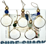 Six white scallop shells with gilded edges, each paired with colored round beads and hanging on natural twine loops, arranged on a printed Surf Shack background.