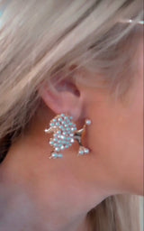 Earring shaped like a poodle made from small pearls worn on a person's ear, featuring a detailed pearl cluster body and tail with gold accents.
