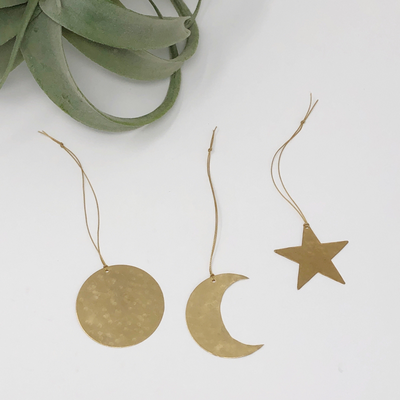 Three hand-cut hammered brass celestial shaped ornaments hanging indoors