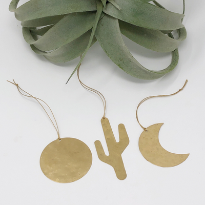 Three brass Sonoran ornaments with hanging cords arranged together