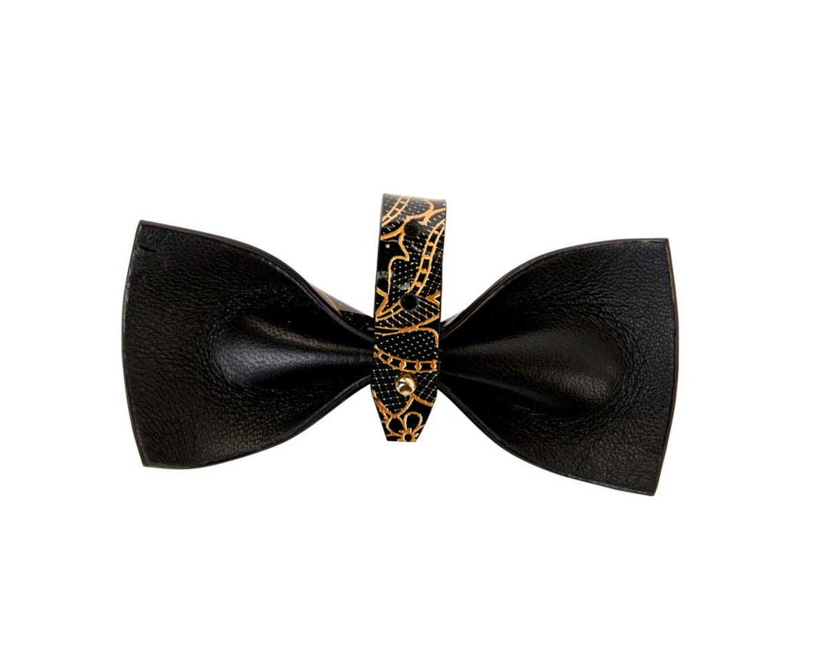 Black patent Italian leather bowtie with a textured finish, featuring a central band adorned with a black and gold floral print.