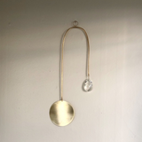 Golden Hour Suncatcher featuring hand forged brass wire and vintage glass crystal, displayed on wall