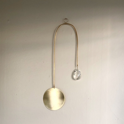 Golden Hour Suncatcher featuring hand forged brass wire and vintage glass crystal, displayed on wall