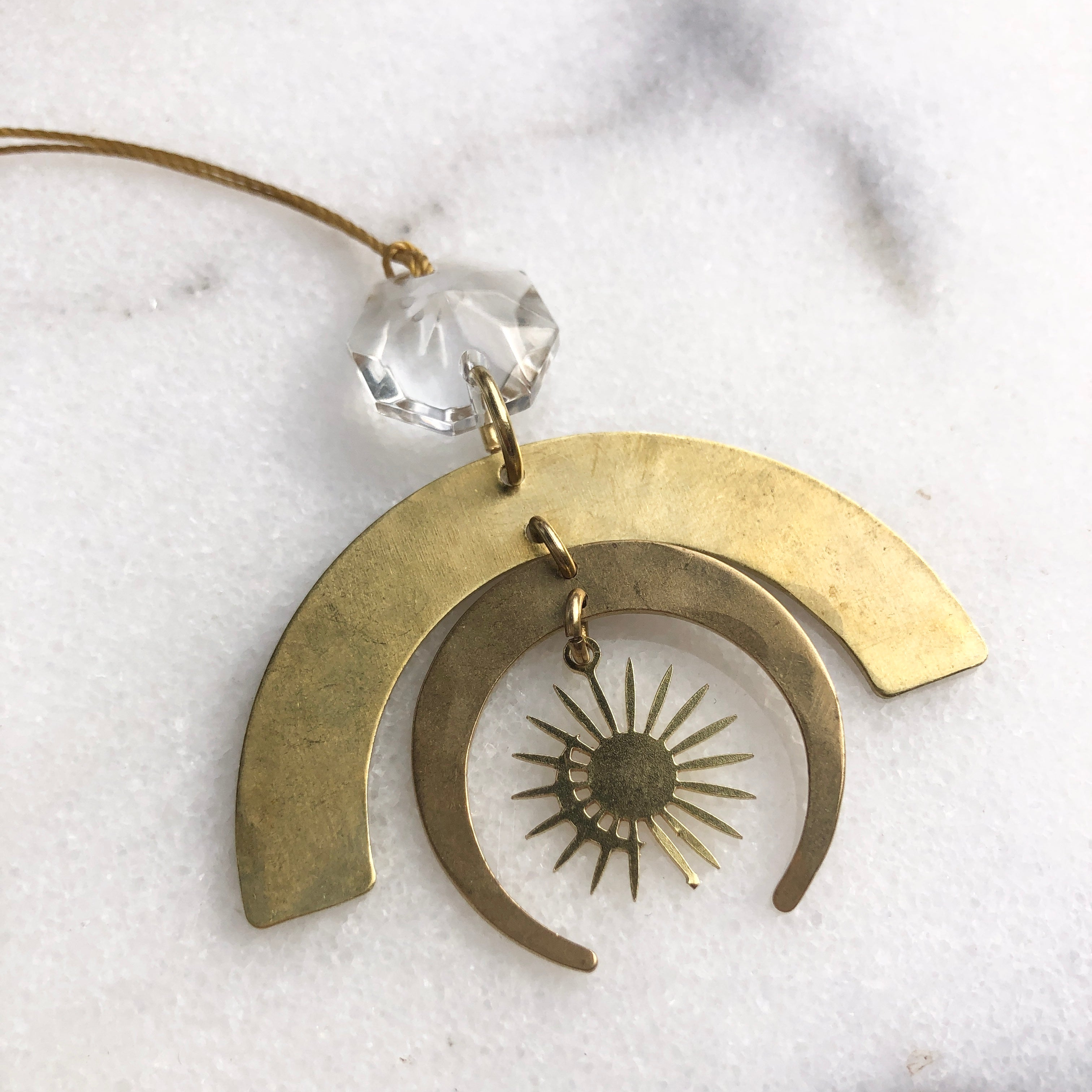 Casseopeia Ornament hanging against a neutral background showing hammered brass with a vintage glass crystal