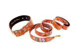 Orange floral-patterned dog collar and matching leash set with gold-tone buckle and clasp, featuring detailed small blossoms on textured leather.