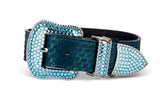Matte blue-green iridescent belt with snake-scale texture and sparkling blue Swarovski crystal-encrusted buckle and loops on black background.