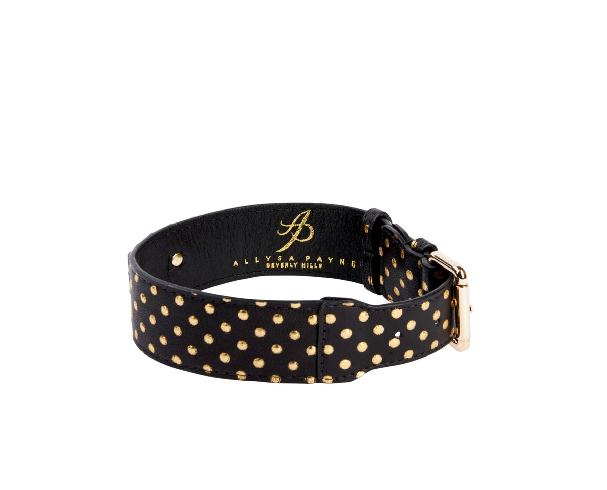 Black leather dog collar with evenly spaced small gold polka dots and a gold metal buckle, styled in a circle with brand name embossed inside.