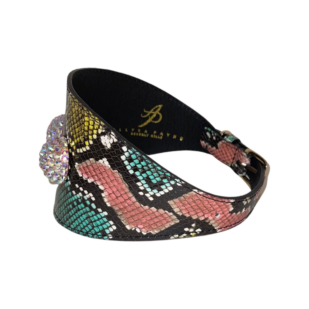 Wide leather dog collar embossed with multicolor snake pattern in teal, pink, and yellow, featuring a large custom Swarovski crystal embellishment on the side.